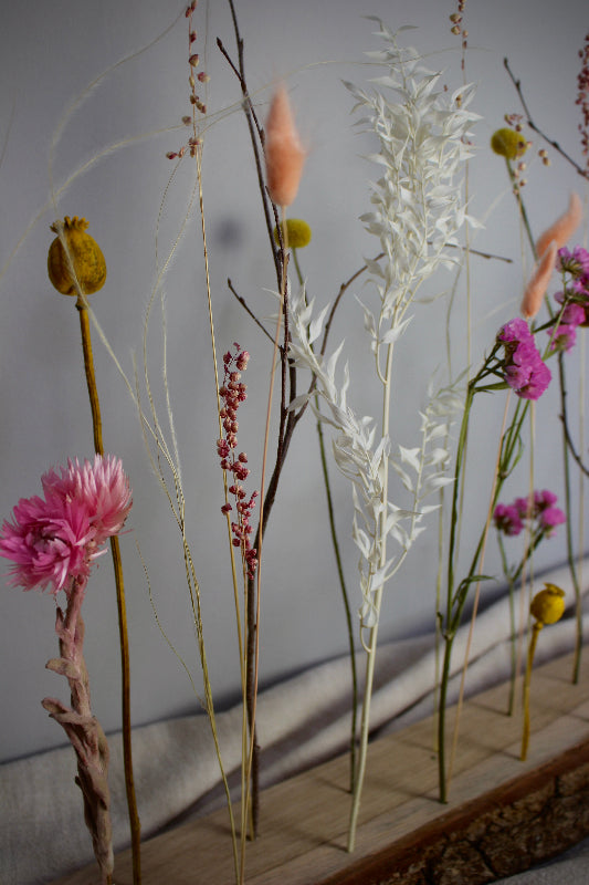 Blütenleiste ‚Frühlingserwachen‘ - DIY Set. Trockenblumen in Pink, Gelb und Weiß treffen auf naturbelassenes Eichenholz mit markanter Rinde.