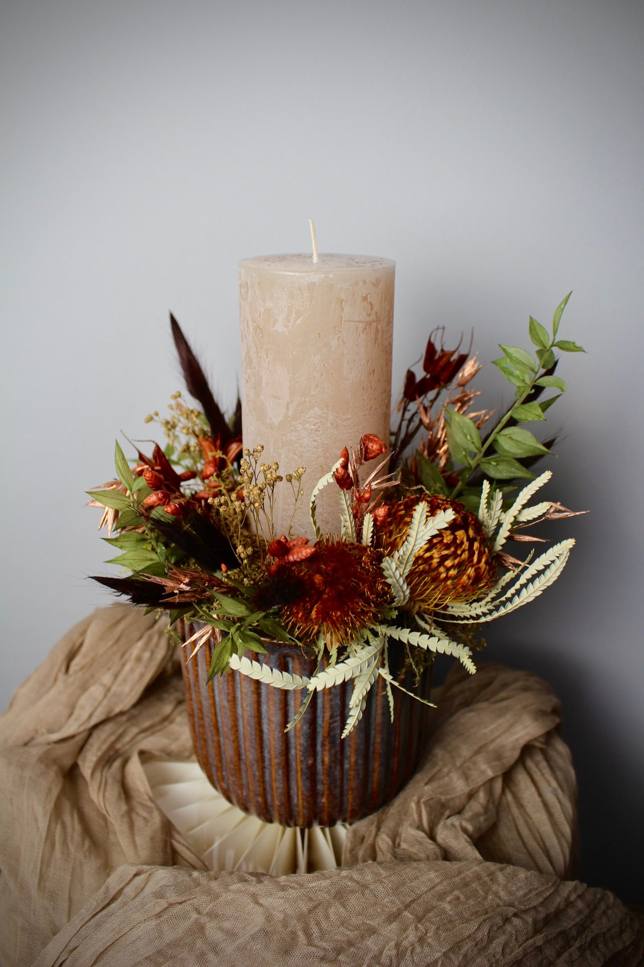 Kerzenarrangement mit Trockenblumen in Keramikvase in Braun- und Naturtönen