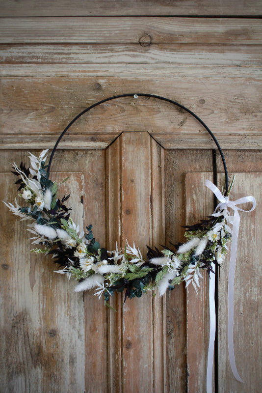 Trockenblumen Loop 'Vellora' in Schwarz und Weiß mit grünen Akzenten. Auf einem schwarzen Metallring gebunden