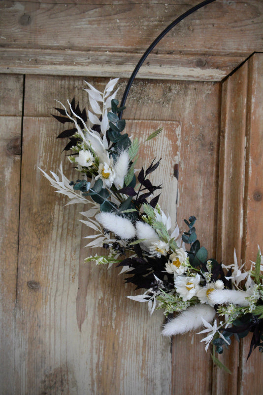 Trockenblumen Loop 'Vellora' in Schwarz und Weiß mit grünen Akzenten. Auf einem schwarzen Metallring gebunden