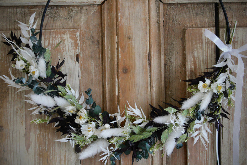 Trockenblumen Loop 'Vellora' in Schwarz und Weiß mit grünen Akzenten. Auf einem schwarzen Metallring gebunden